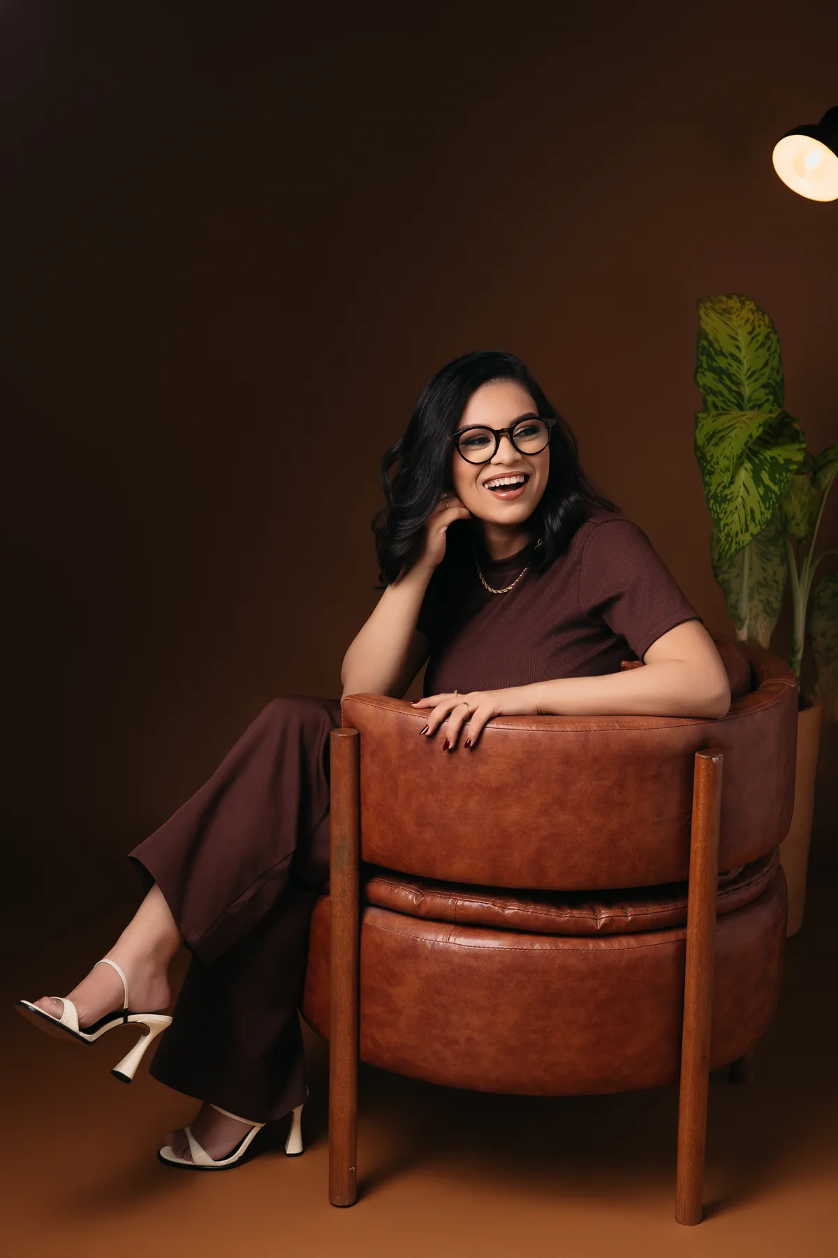 Vitória Gonçalves, nutricionista, rindo, sentada numa poltrona de couro